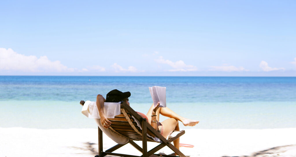 Photo by Chen Mizrach on Unsplash. Image of person on beach reading a book.